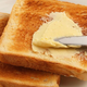Knife slathering butter onto toast